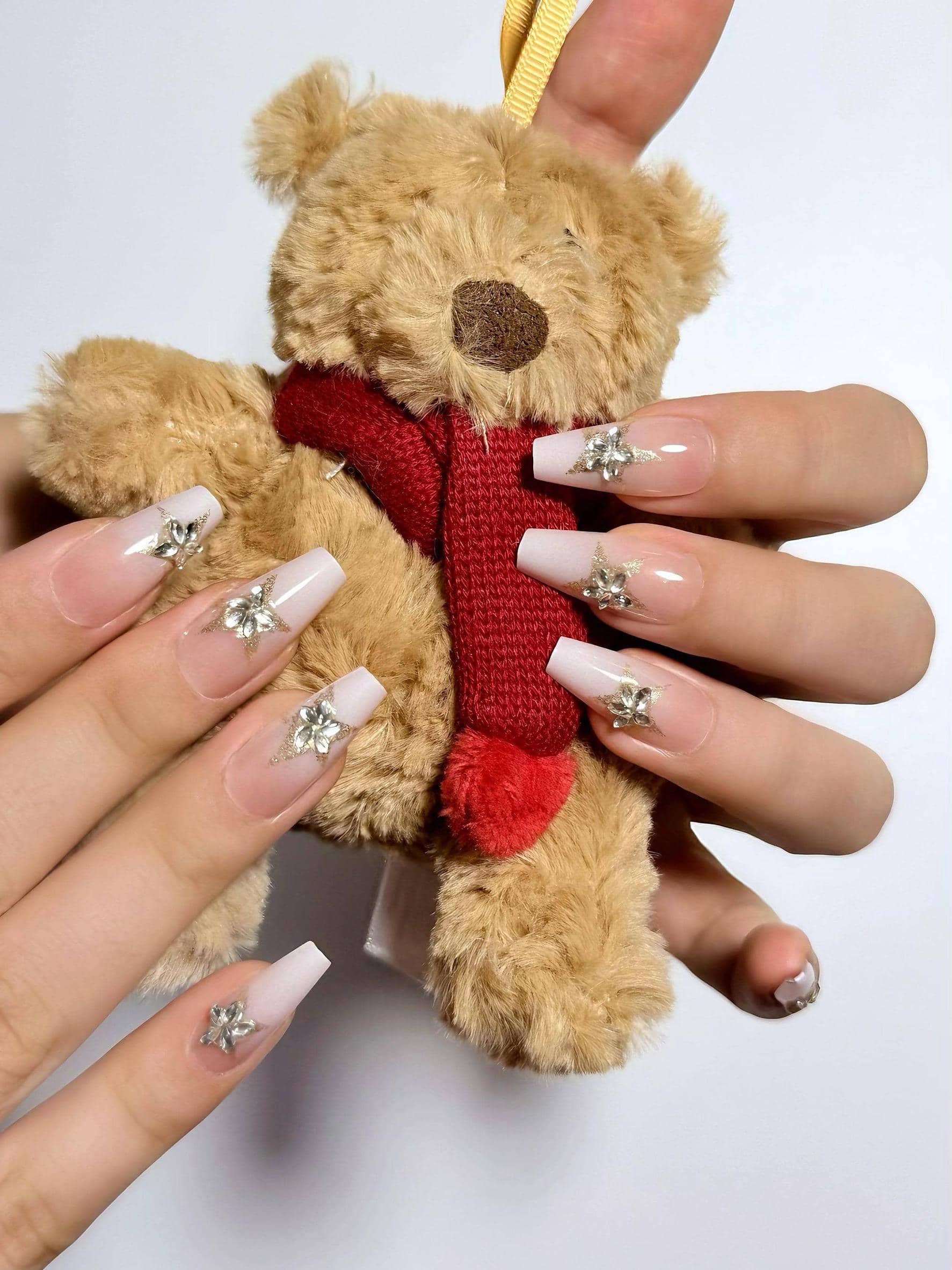 Clean glossy ombre press on nails in soft white tones, adorned with sparkling diamond star accents. Perfect for daily wear, office, holidays and weddings. Medium length coffin shape fake nails with a sleek, elegant finish.
