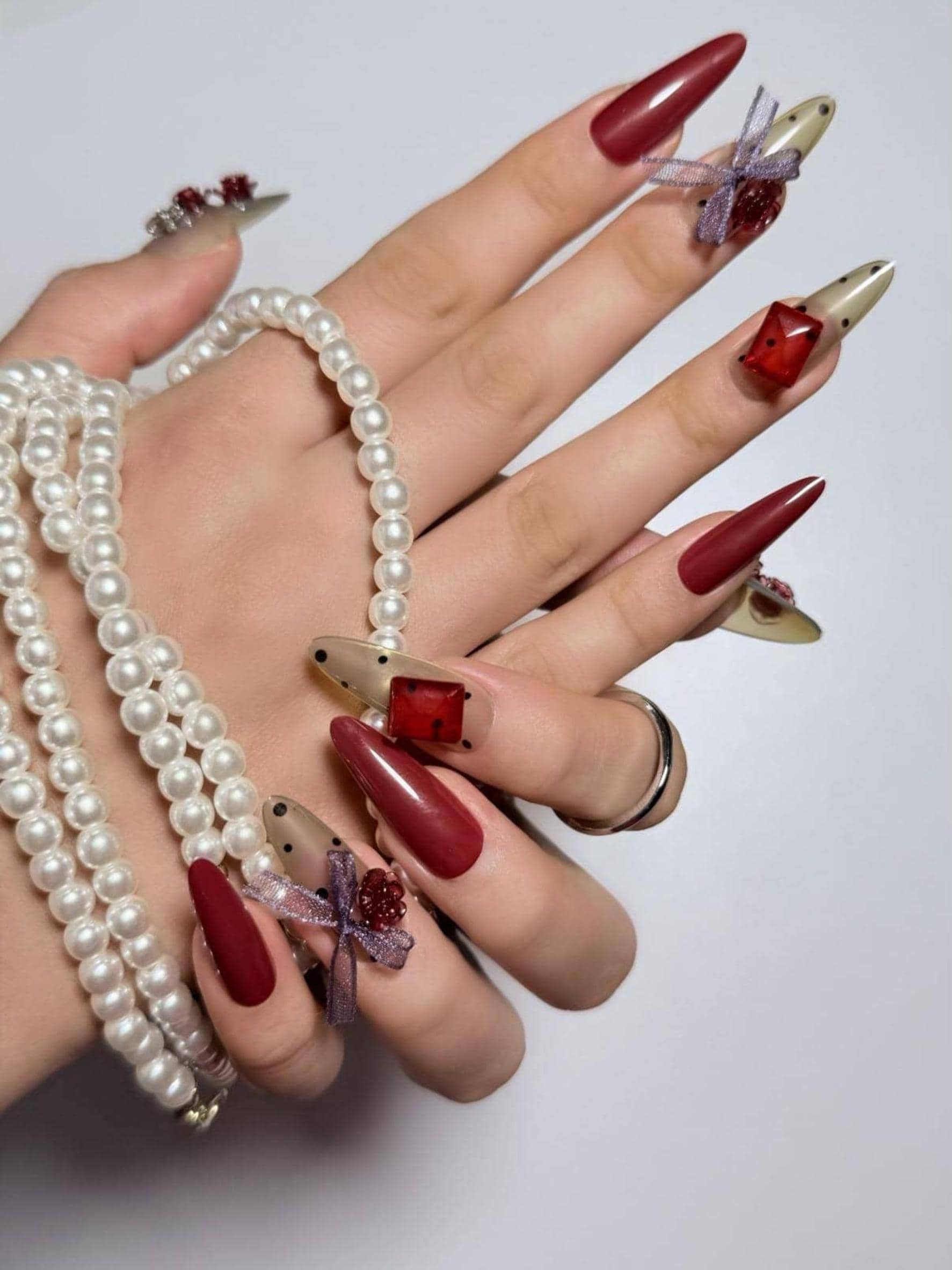 Bold red press on nails adorned with huge rhinestones, 3D rose charms, ribbon accents and polka dot details. Perfect for parties, dates and daily use. Long almond shape fake nails with a glamorous, romantic finish.