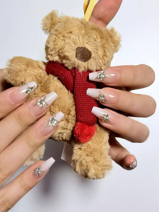 Clean glossy ombre press on nails in soft white tones, adorned with sparkling diamond star accents. Perfect for daily wear, office, holidays and weddings. Medium length coffin shape fake nails with a sleek, elegant finish.