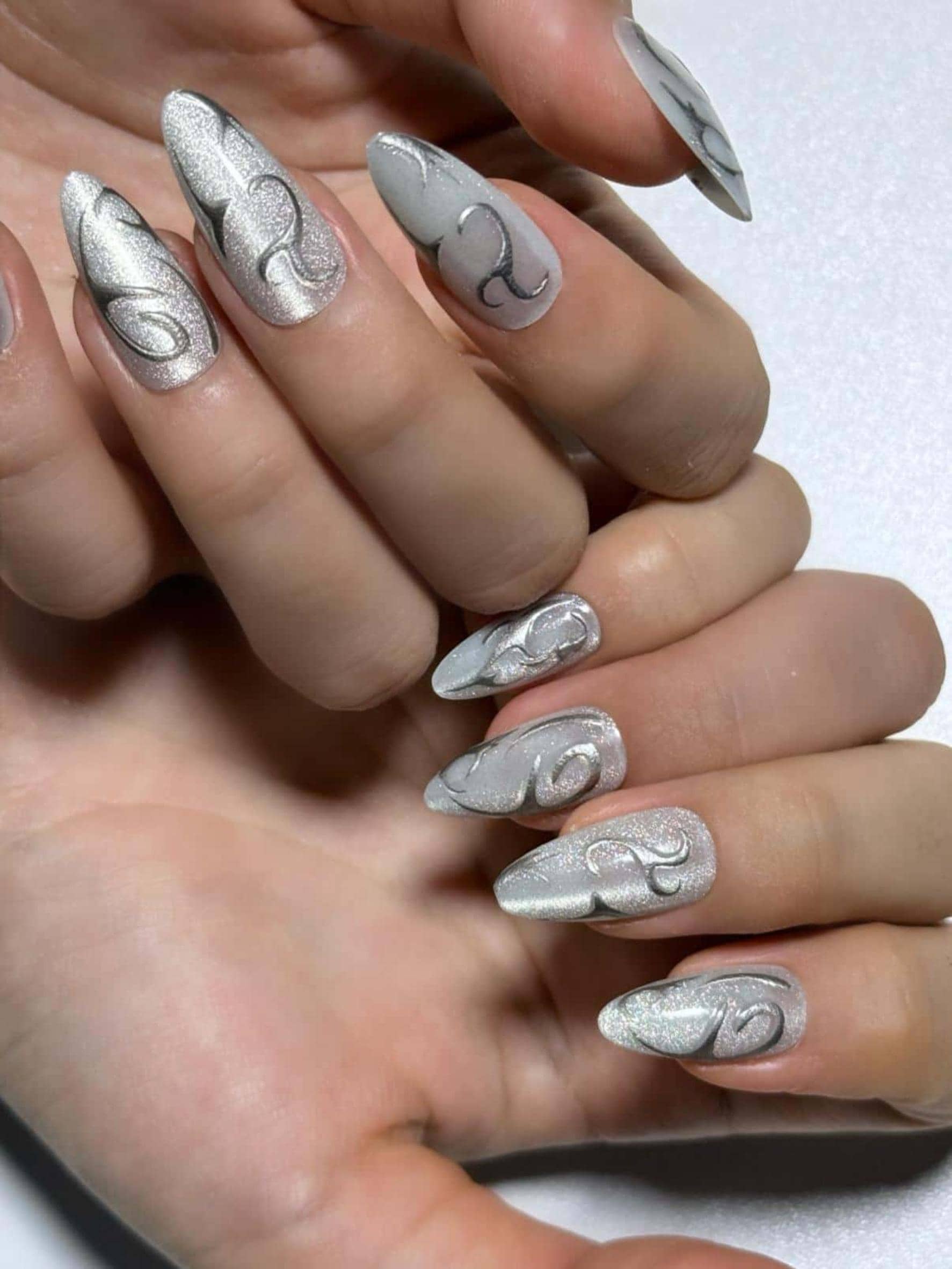 Swirl silver line white cat eye press on nails with a shimmery finish. Perfect for daily use, office, parties and holidays. Medium length almond shape fake nails with a sleek, futuristic vibe.